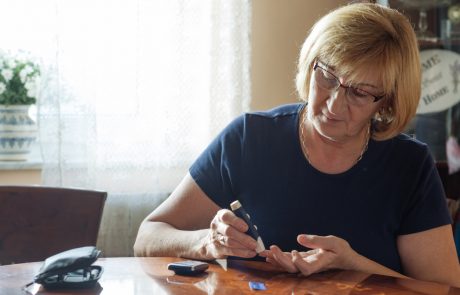 Senior woman in her 60s using sugar blood test to check the sugar level in blood stream. Woman is living life with chronic illness everyday and overcoming challenges that illness brings.