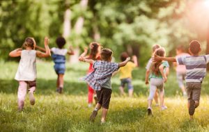 Back view of carefree kids having fun while running in springtime.