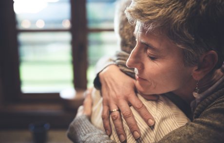 Senior couple embrace themselves in their kitchen