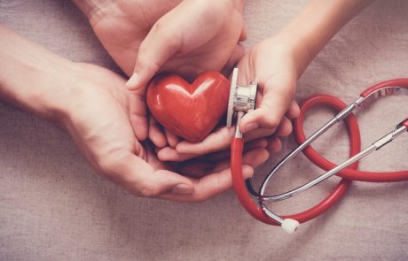 child and adult holding red heart with stethoscope, heart health, health insurance concept