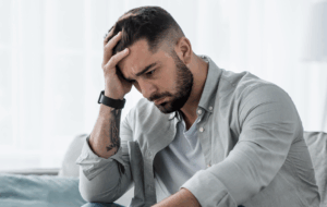 Attraktive Kerl Gefühl verzweifelt, traurig, Blick beunruhigt depressiv nachdenklich und einsam leiden Depressionen auf der Couch zu Hause im mittleren Alter Krise, psychische Gesundheit persönliche Probleme und Lebensstil