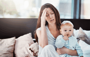 Mutter, Baby und Müde oder Stress in einem Wohnzimmer oder Bett mit Postpartum, Kopfschmerzen oder Angst. Depression, psychische Gesundheit und Brennen einer Frau oder Mutter mit einem Kind in einem ermüdeten Familienhaus
