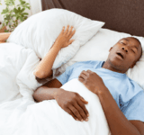 Gesundheitsprobleme, Tiefschlaf und Apnoe, Lärm und schlechte Nacht. Junger afrikanischer amerikaner kerl schnarchen, dame leiden und bedecken sie gesicht mit kissen so nicht hören mann im bett im schlafzimmer innenraum, leere raum