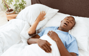 Gesundheitsprobleme, Tiefschlaf und Apnoe, Lärm und schlechte Nacht. Junger afrikanischer amerikaner kerl schnarchen, dame leiden und bedecken sie gesicht mit kissen so nicht hören mann im bett im schlafzimmer innenraum, leere raum