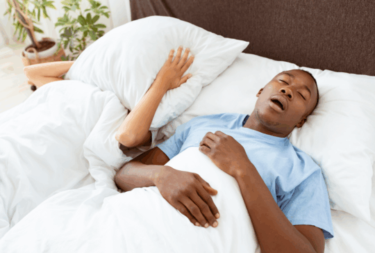 Gesundheitsprobleme, Tiefschlaf und Apnoe, Lärm und schlechte Nacht. Junger afrikanischer amerikaner kerl schnarchen, dame leiden und bedecken sie gesicht mit kissen so nicht hören mann im bett im schlafzimmer innenraum, leere raum