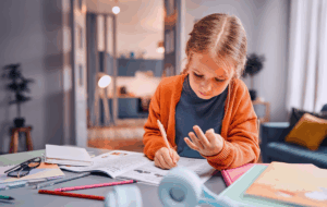 Kinder lernen Mathematik. Pensive blonde Mädchen sitzt am Desktop und löst arithmetische Aufgaben, während sie auf Finger zählt. Independent Kid entwickelt mentale Fähigkeiten und verbessert die Abrechnung im Kopf.