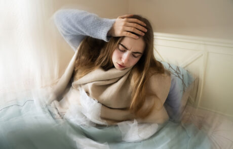 Kranke junge weiße Frau, die aus dem Bett steigt, ihren Kopf aufgrund von Schwindel, Migräne, Schwindel, Kopfschmerzen im Schlafzimmer zu Hause hält. Saisonale Kälteerscheinungen, Grippeepidemie, Fieber, Krankheit, Krankheit, Unwohlsein.