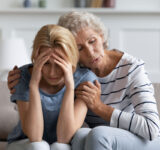 Wir werden es überwinden, lieber Schatz. ängstlich liebevolle, heimatliche Mutter beruhigend, tränkend unterstützende, depressive erwachsene Tochter leidet an schlechten Tag, Gesundheit oder Arbeitsschwierigkeiten, gefährliche Diagnose, Scheidung