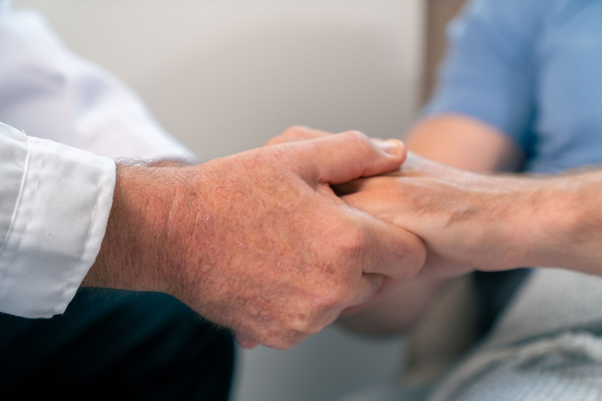 Arzt, der die Hände hält und den männlichen Patienten beruhigt. Medizinische Gesundheitsversorgung, Krankheitsdiagnose und Unterstützung bei der Kommunikation mit Empathie. Gesundheitstherapie, Psychotherapie, Wellnessberatung in der Klinik.