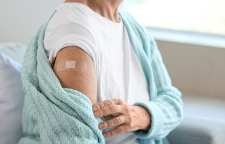 Seniorin mit Pflaster sitzt nach Impfung zu Hause auf dem Sofa, Nahaufnahme