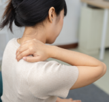 Frauen, die ihren Nacken in Schmerzen berühren, während sie zu Hause sitzen. Nackenschmerzen, Muskelspannung, Schulteranstrengung und Gesundheitskonzept.