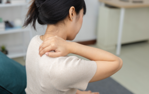Frauen, die ihren Nacken in Schmerzen berühren, während sie zu Hause sitzen. Nackenschmerzen, Muskelspannung, Schulteranstrengung und Gesundheitskonzept.