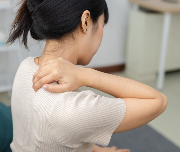 Frauen, die ihren Nacken in Schmerzen berühren, während sie zu Hause sitzen. Nackenschmerzen, Muskelspannung, Schulteranstrengung und Gesundheitskonzept.