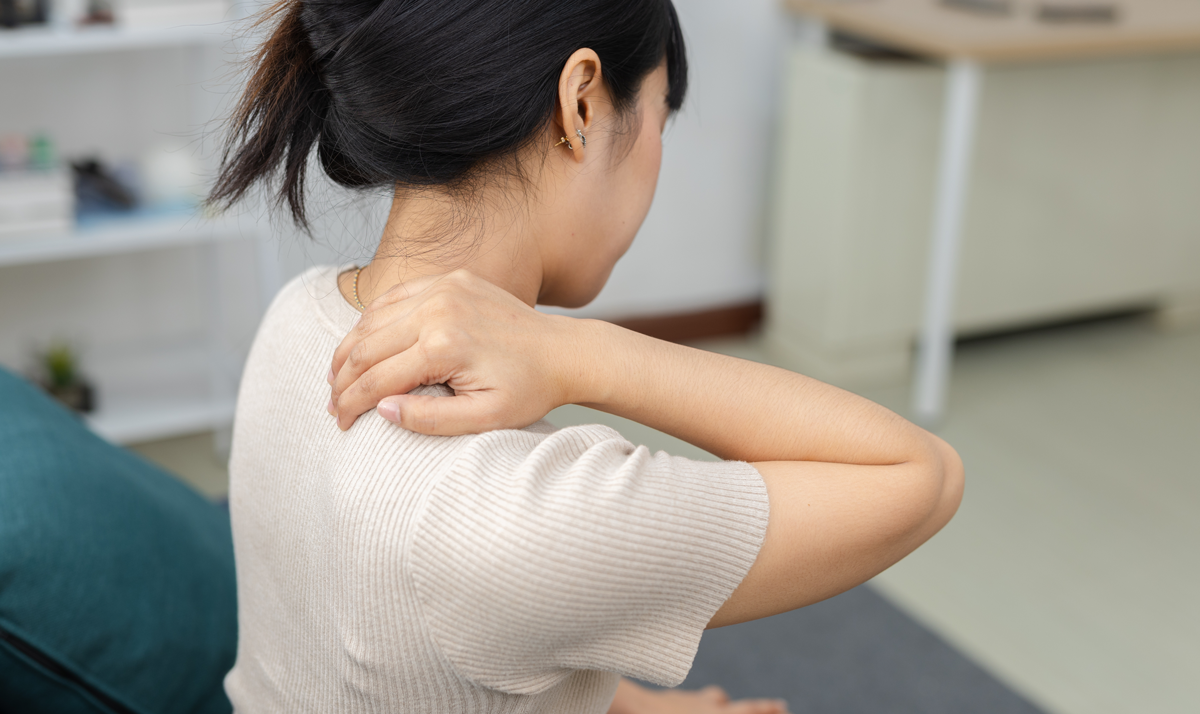 Frauen, die ihren Nacken in Schmerzen berühren, während sie zu Hause sitzen. Nackenschmerzen, Muskelspannung, Schulteranstrengung und Gesundheitskonzept.