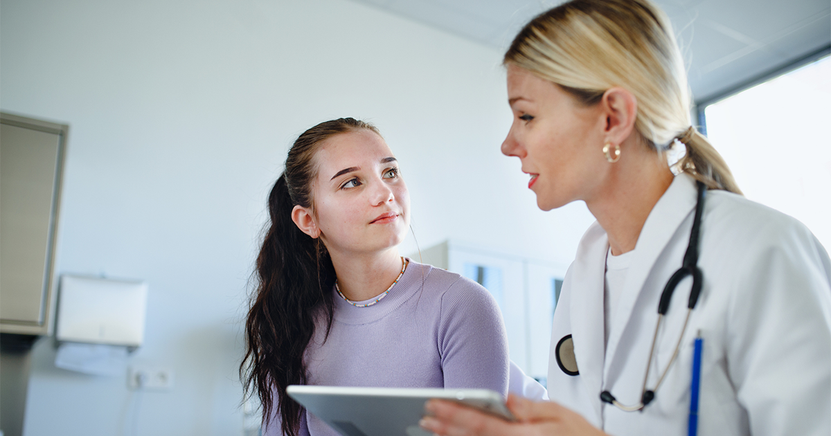 Young woman doctor explaining diagnosis to teenage girl