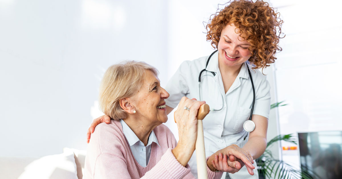 Friendly relationship between smiling caregiver in uniform and happy elderly woman.
