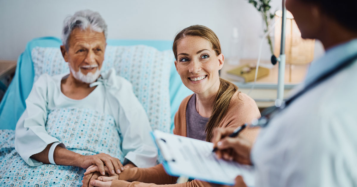 Happy woman and her hospitalized father talking to a doctor at the clinic