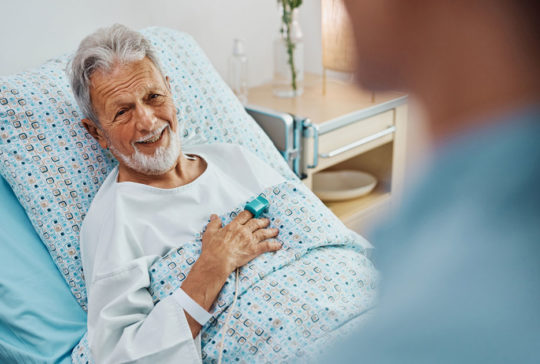 Happy senior patient talking to a nurse while recovering in the hospital ward.