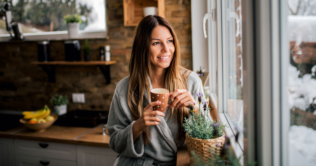 Young woman drinking coffee in the morning, looking at window