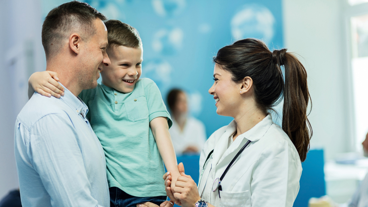 Happy female doctor giving high fie to a little boy who came with father at hospital.