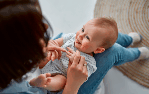 Loving mom carying of her newborn baby at home.Mom and baby boy playing in sunny bedroom. Parent and little kid relaxing at home. Family having fun together. Childcare, maternity concept