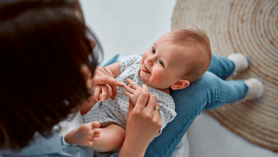 Loving mom carying of her newborn baby at home.Mom and baby boy playing in sunny bedroom. Parent and little kid relaxing at home. Family having fun together. Childcare, maternity concept
