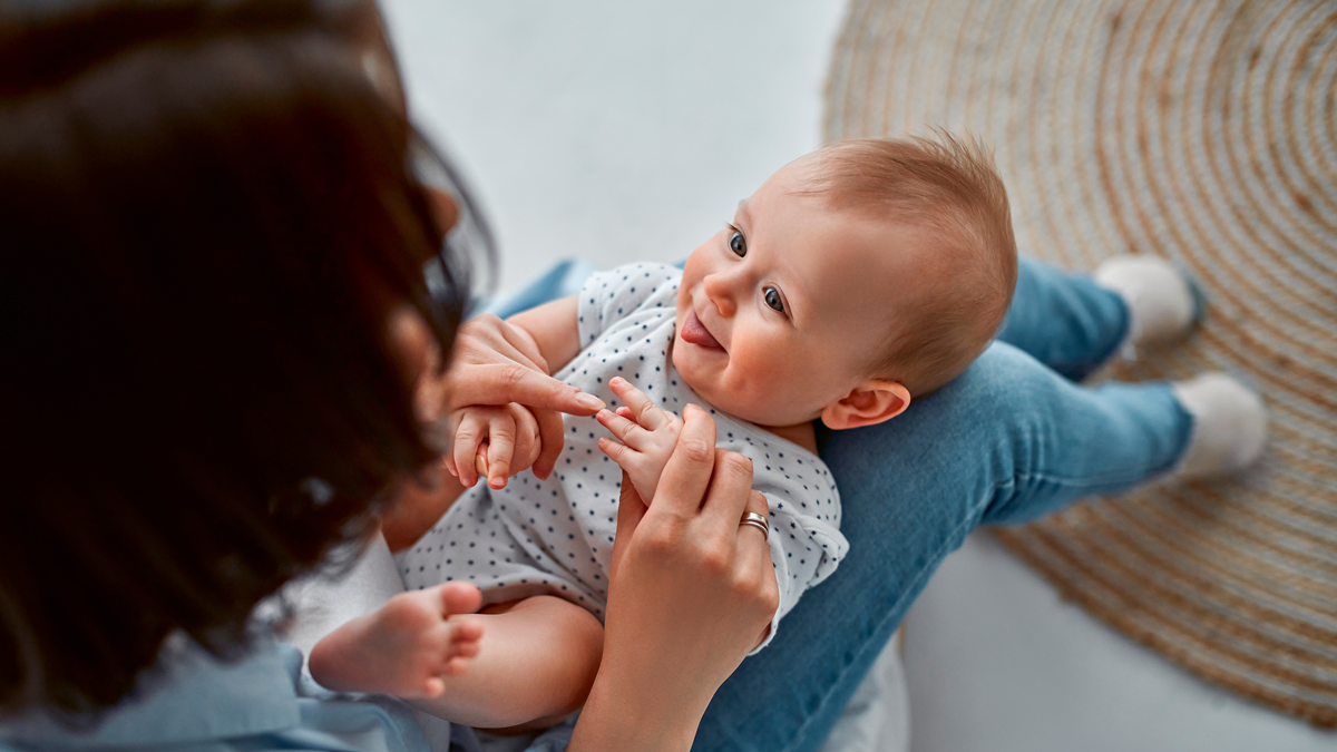 Loving mom carying of her newborn baby at home.Mom and baby boy playing in sunny bedroom. Parent and little kid relaxing at home. Family having fun together. Childcare, maternity concept