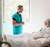 Surgeon Visiting And Talking With Mature Female Patient In Hospital Bed