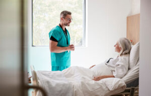 Surgeon Visiting And Talking With Mature Female Patient In Hospital Bed
