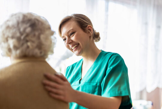 Friendly nurse supporting an elderly lady