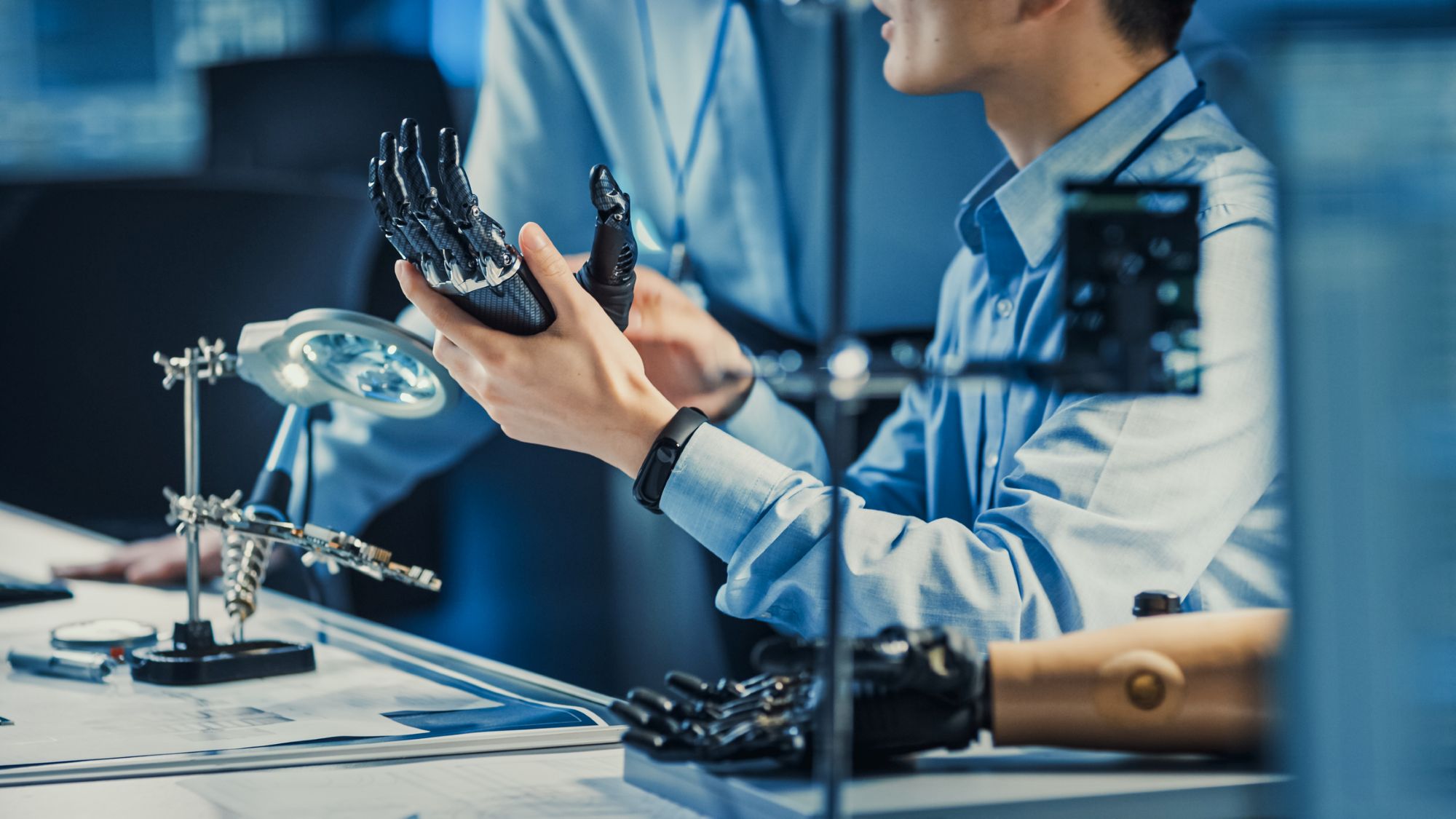 Technological Prosthetic Robot Arm is Tested by Two Professional Development Engineers in a High Tech Research Laboratory with Modern Futuristic Equipment. Compare Data on a Personal Computer.