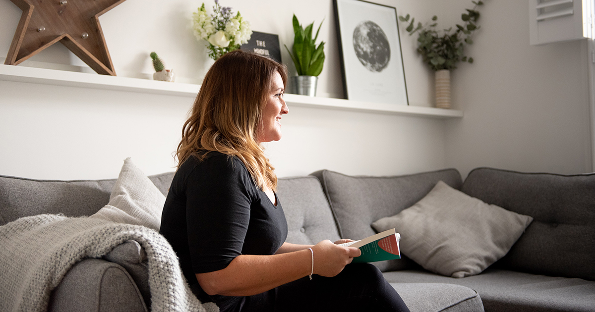 Vrouw met boek in haar woonkamer