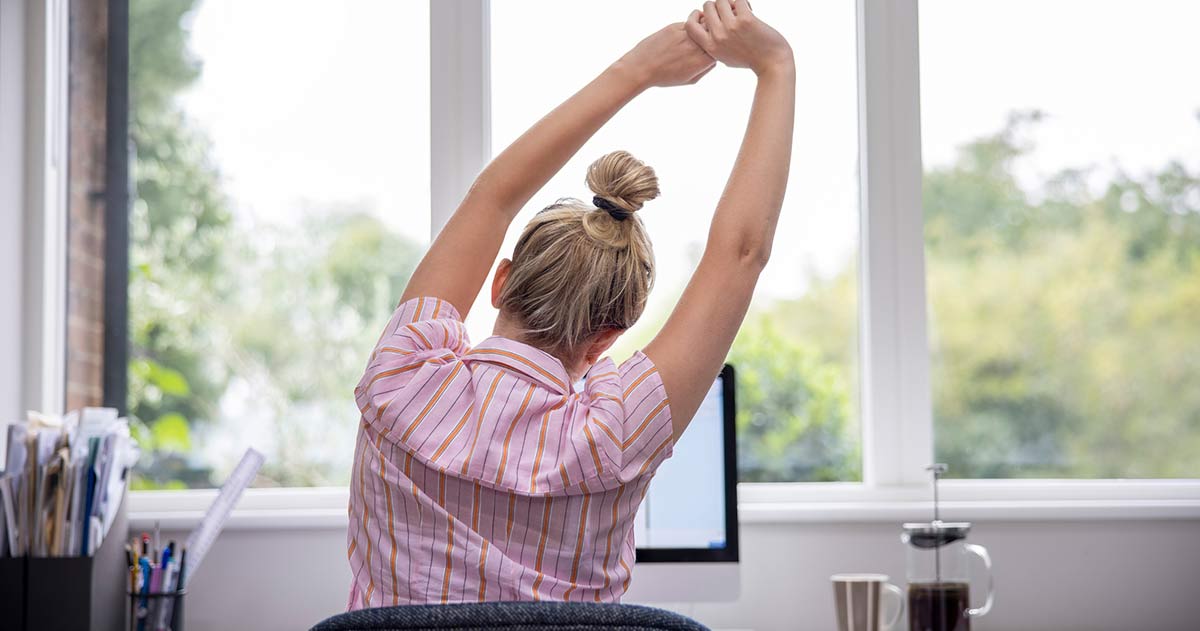 Vrouw strekt zich uit achter haar bureau