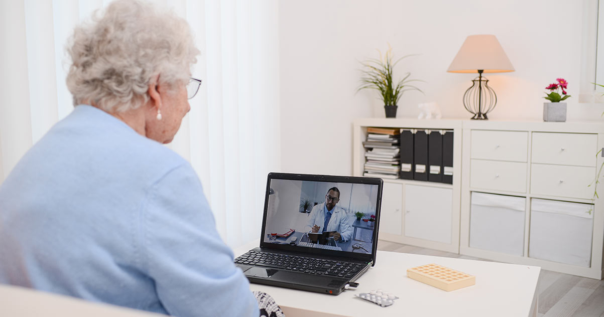 Oude vrouw zit op de bank met een digitaal consult met haar arts