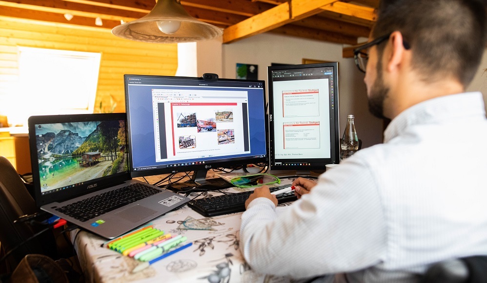 A so-called laptopjockey in his home office watching three big screens