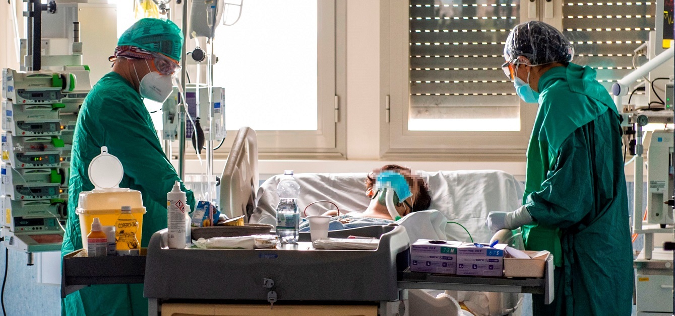 Two doctors standing next to a patient in a bed in a Coronavirus-hospital