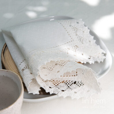 Hullmønstret hvit serviett i lin med blonder.