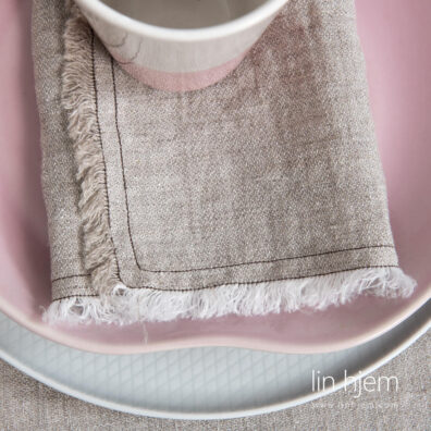 Vasket linserviett i lys grå med frynser.