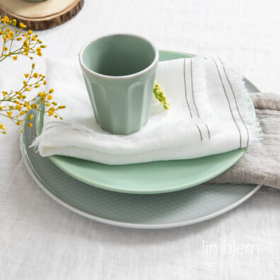 Linserviett i melkehvit farge med frynser, vasket.