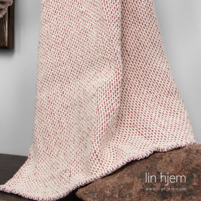 Rødt/hvit mønstret håndkle i halvlin.