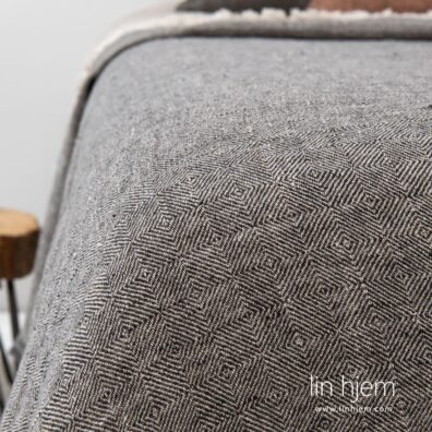 Grått sengeteppe av lin.