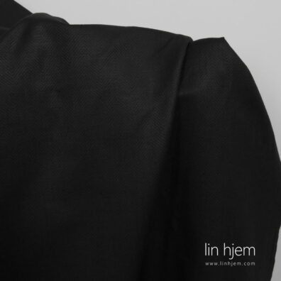 Halvlin svart stoff i gran mønster.