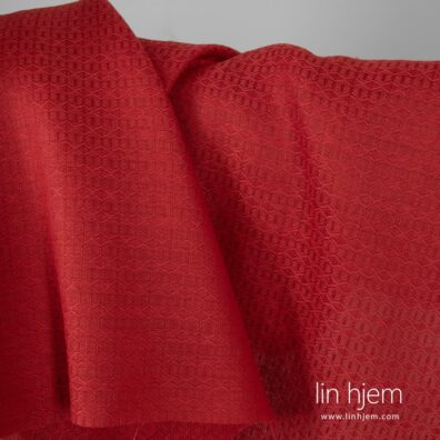 Mønstret halvlin stoff i rød farge.