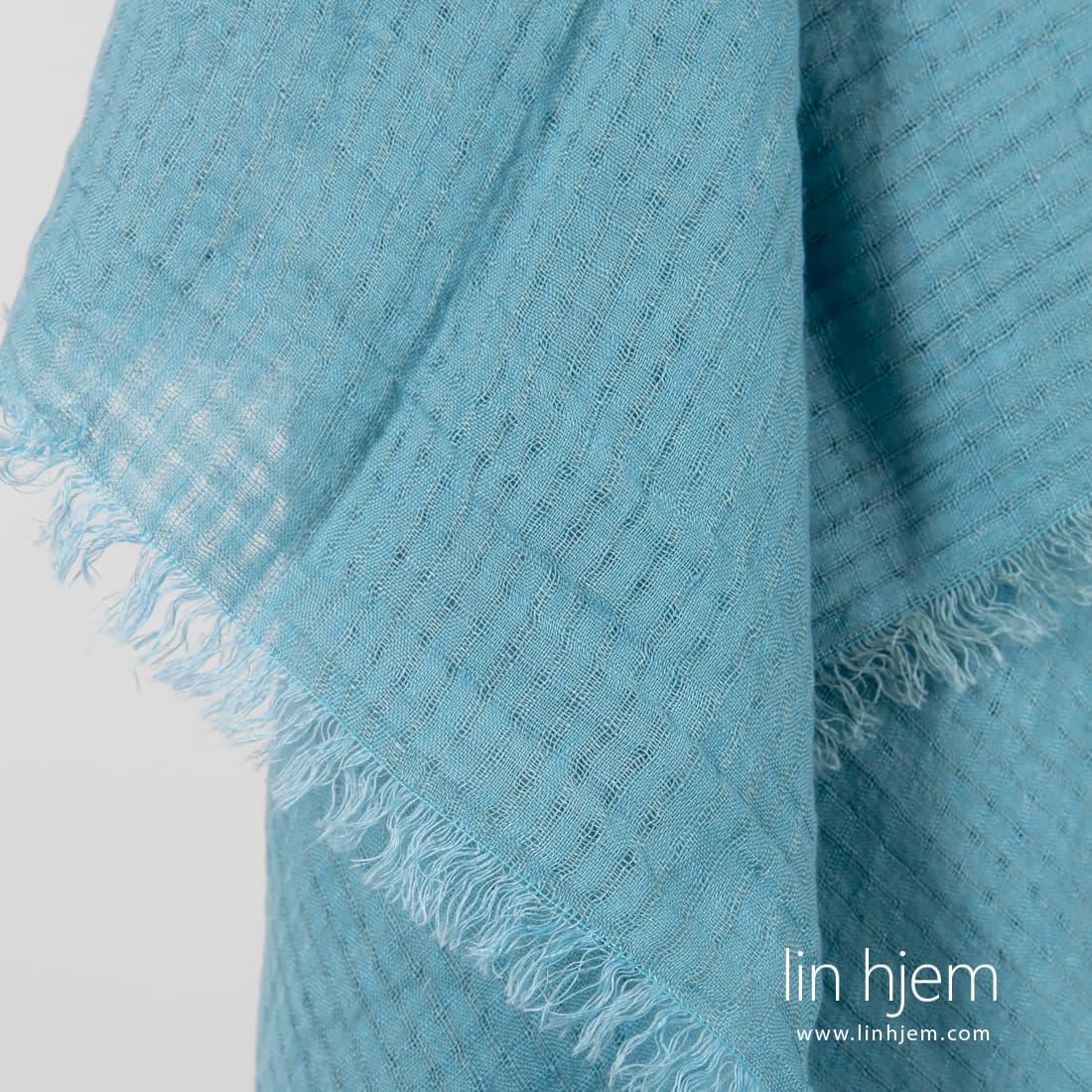 Lyseblått skjerf av linstoff.