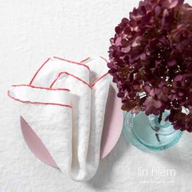 Hvit linserviett med rødaktig kant fra ARVO kolleksjon.