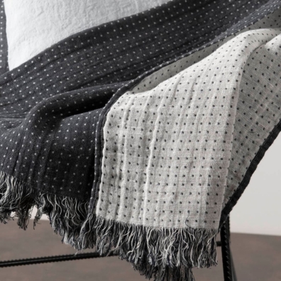 Dobbeltsidig mørkegrå og hvit lin-bomullspledd med prikker og frynser på kortkantene