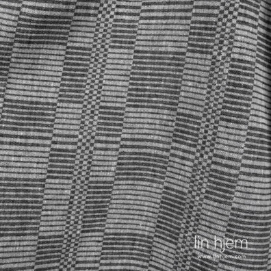 Lyse hvite, svarte og blågrønne garn er vevd i et linstoff med stripet mønster