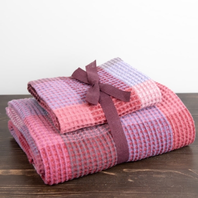 Et sett med lilla håndklær er bundet med et bånd av matchende farge