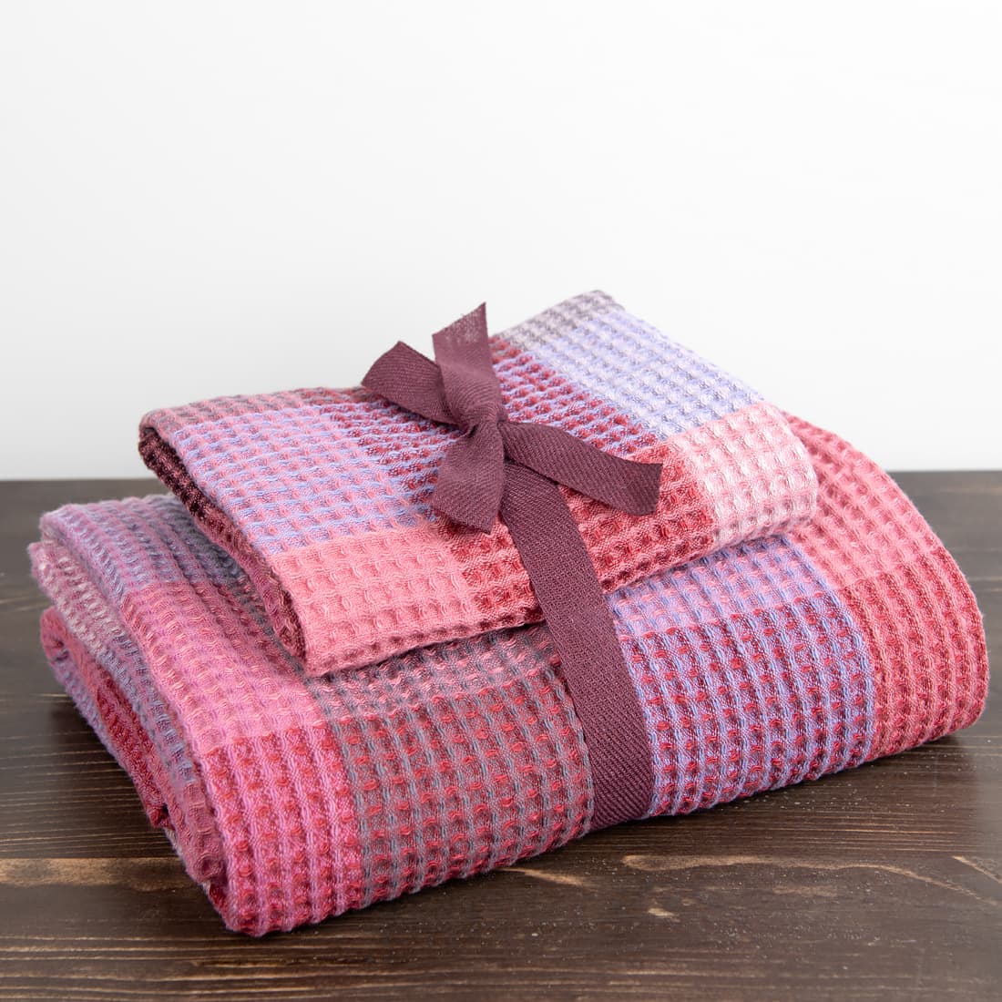 Et sett med lilla håndklær er bundet med et bånd av matchende farge