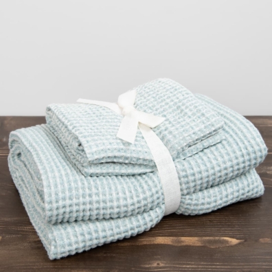 Sett med lyblåaktiggrønn-hvitt håndklær er bundet med et bredt bånd